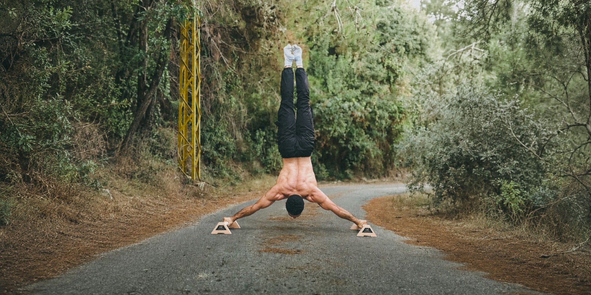 Athlete holding a wide handstand on XENGINEERS X-Parallettes outdoors