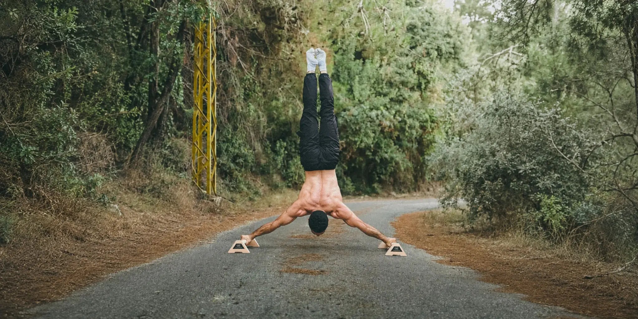 Athlete holding a wide handstand on XENGINEERS X-Parallettes outdoors